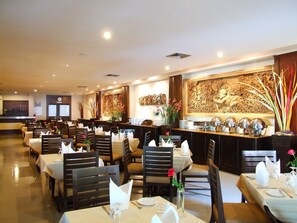 A restaurant with multiple tables, each set with white tablecloths, chairs, and neatly arranged cutlery. - Sarita Chalet & Spa (Pattaya)