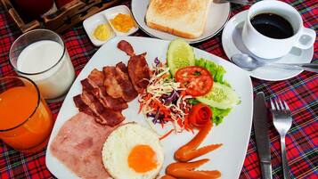 A breakfast plate with bacon, ham, eggs, and vegetables, along with toast, a glass of orange juice, and a cup of coffee.