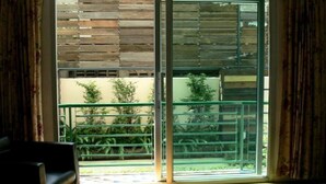 Una habitación con puerta de cristal corredera que da a un balcón con barandilla de metal.