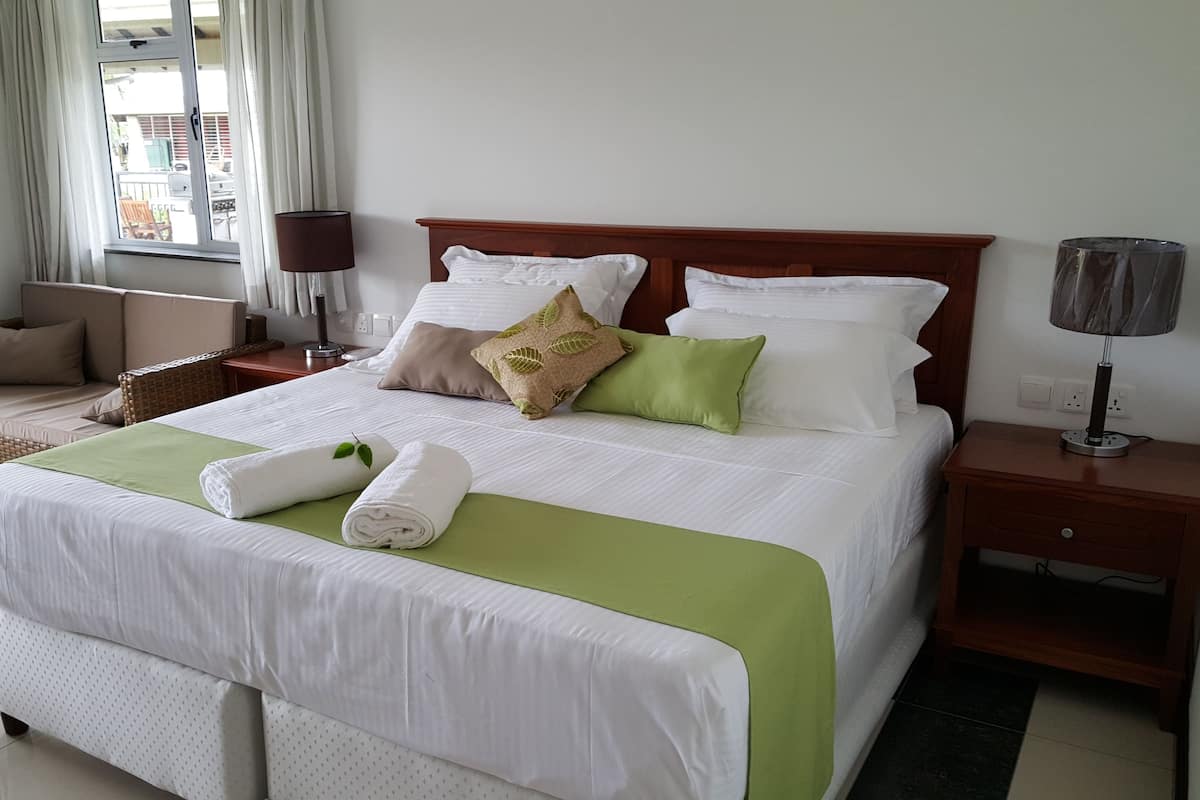 Una cama bien hecha con ropa de cama blanca y verde, un cabecero de madera y varias almohadas.