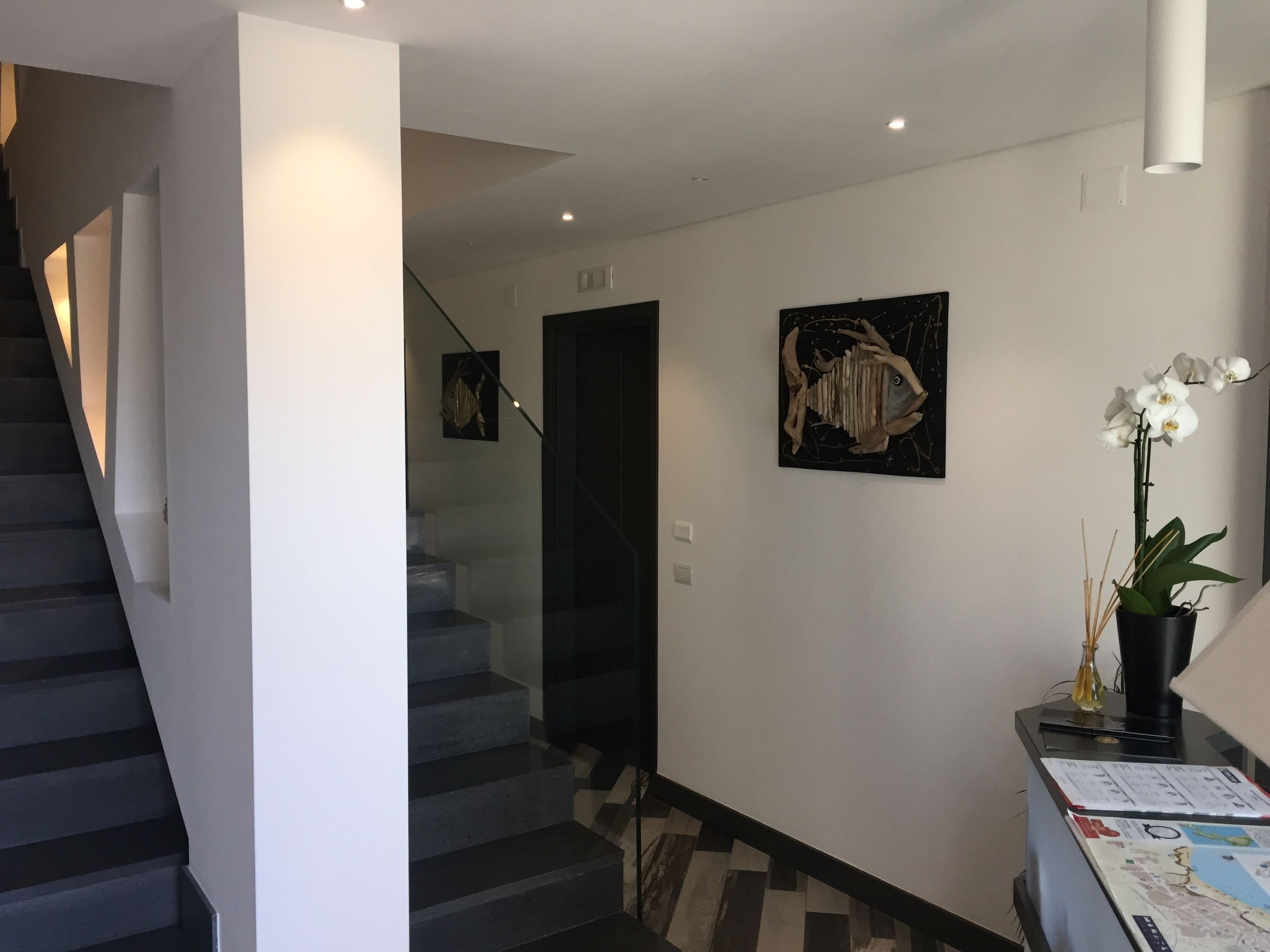 A modern interior with a staircase, a wall-mounted artwork, and a potted orchid.