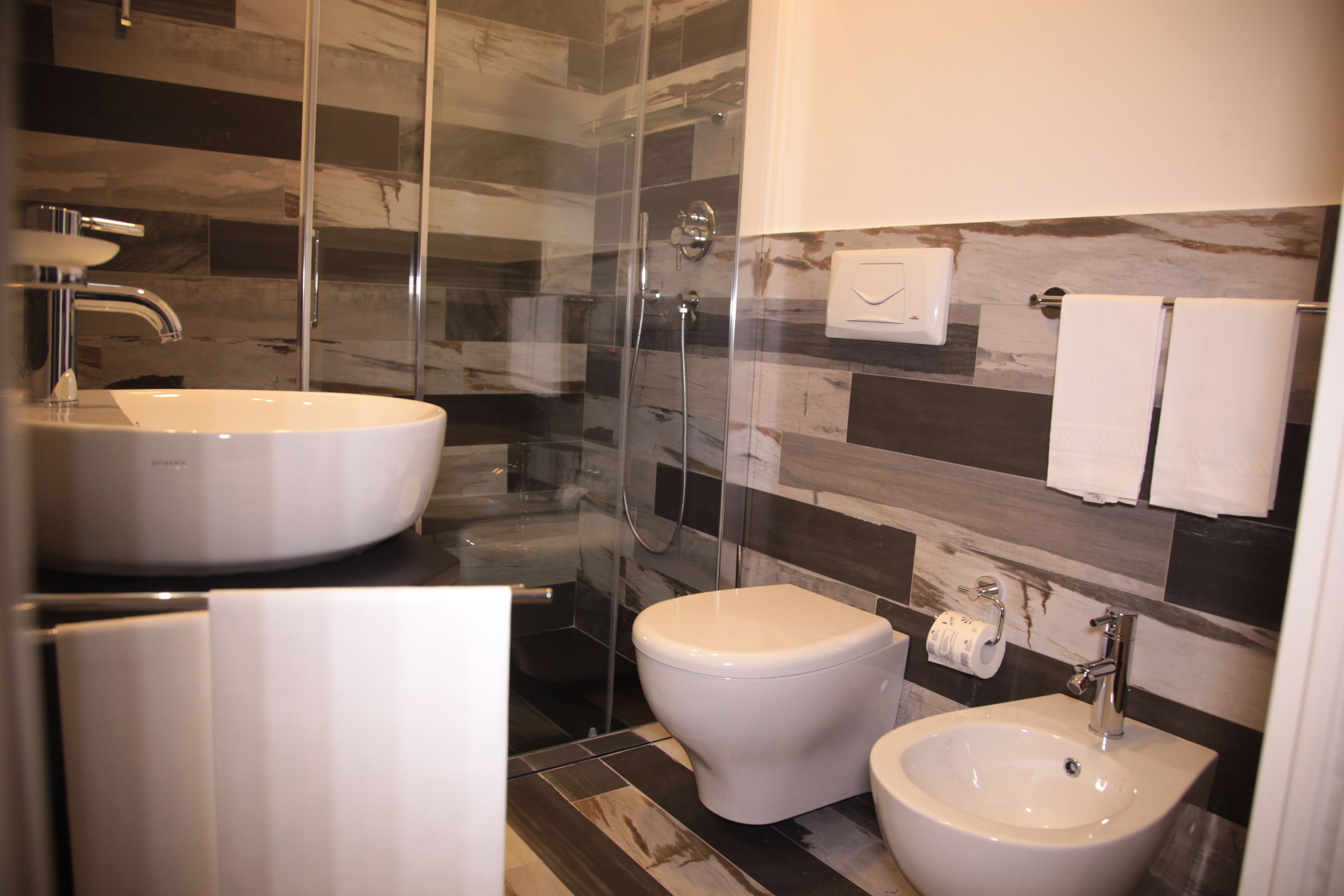 Une salle de bain moderne dotée d’une douche à parois de verre, d’un double lavabo et de toilettes.