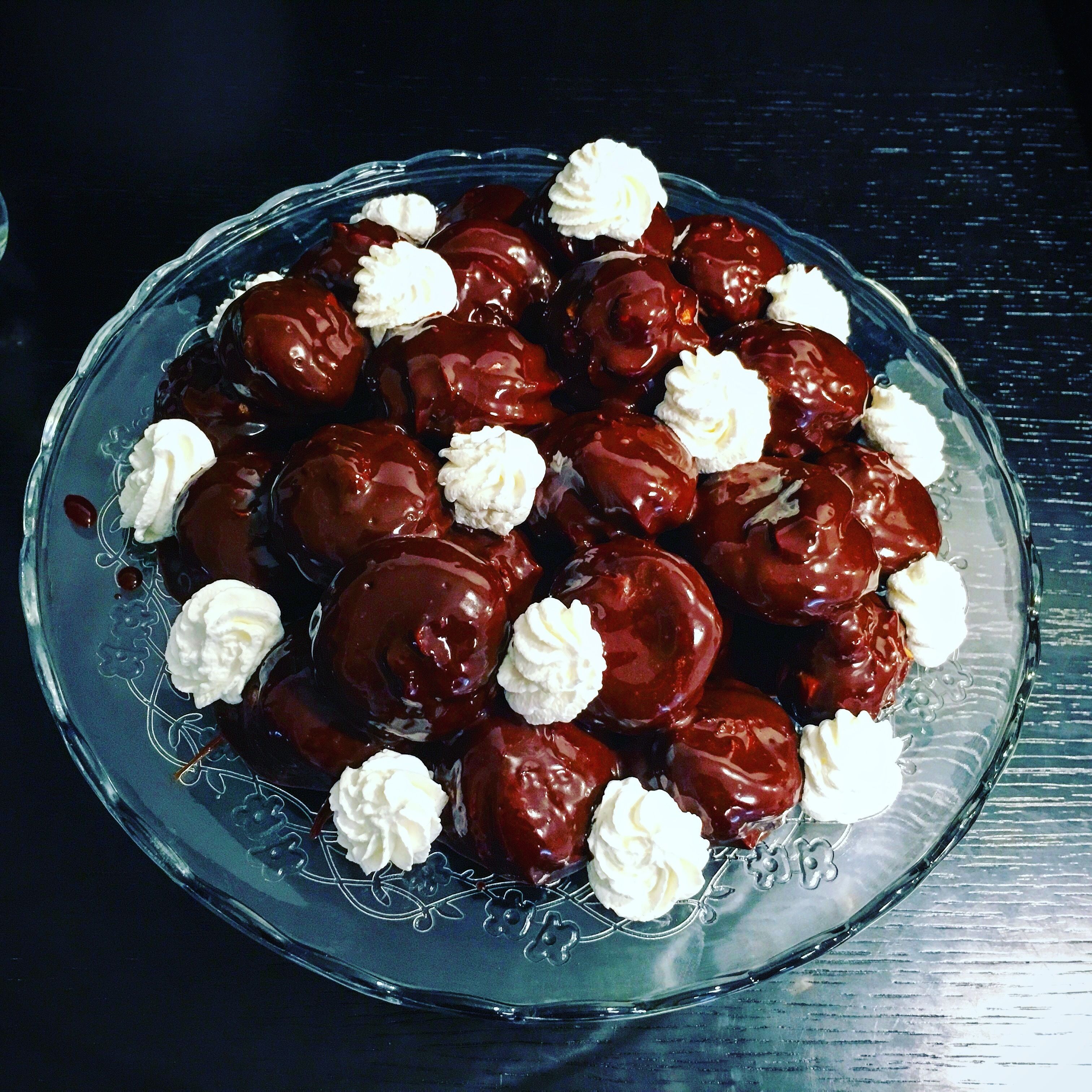 A glass plate with chocolate-covered cherries and whipped cream.