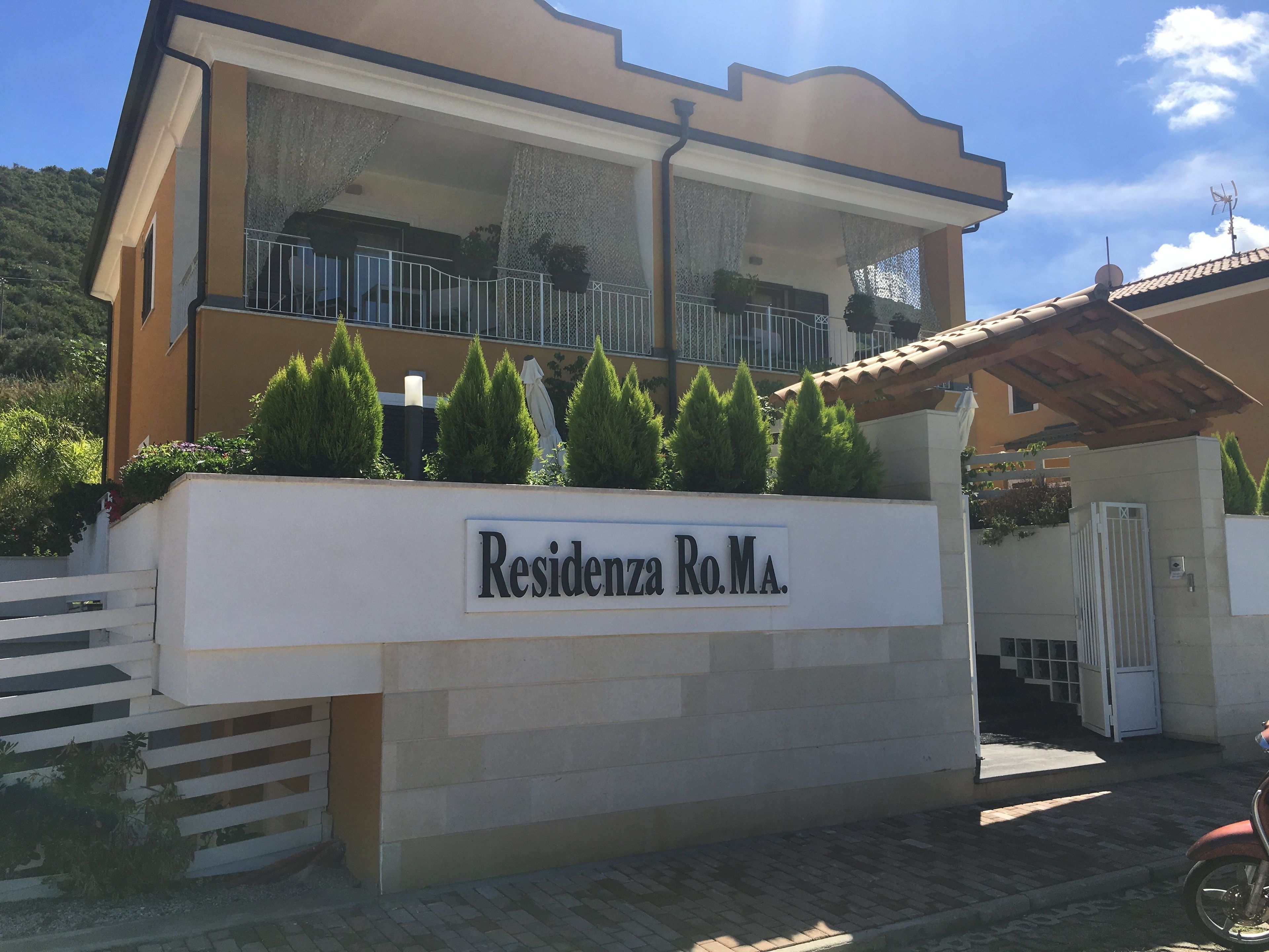 A residential building with a balcony, a sign reading "Residencia Ro.Ma.", and a gate.