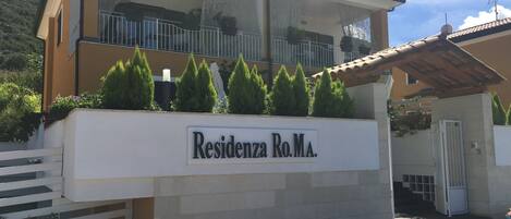 A residential building with a balcony, a sign reading "Residencia Ro.Ma.", and a gate.