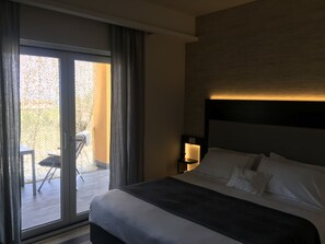 A hotel room with a bed, a nightstand, a lamp, and a sliding glass door leading to an outdoor area. - Residenza RoMa (Tropea)
