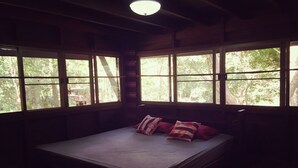 A room with a bed, large windows, and a ceiling light.