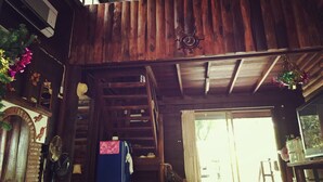 A rustic wooden interior with a staircase, a refrigerator, and a large window.