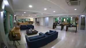 Um hall amplo com sofás, uma mesa de centro e um balcão de recepção.