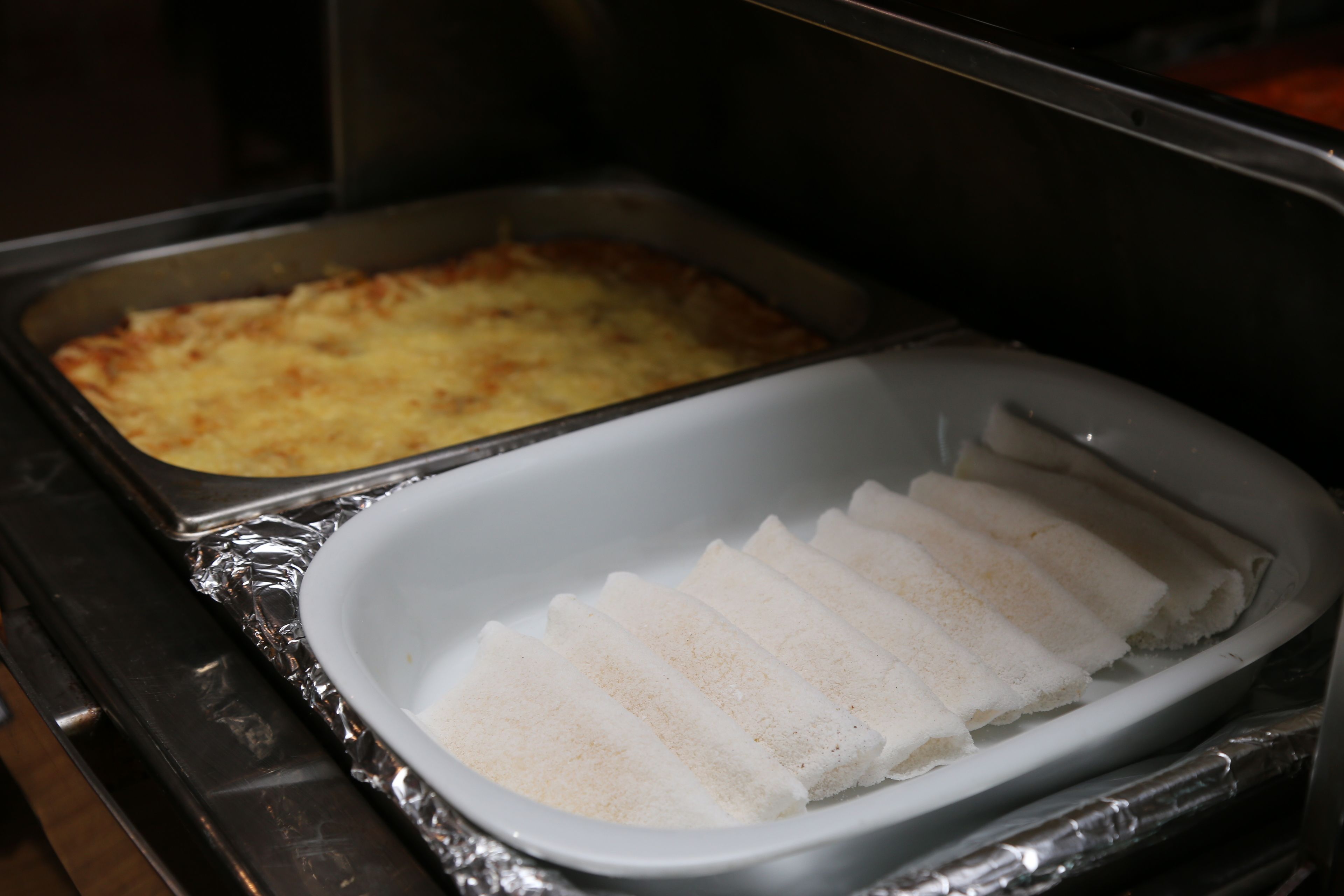 Ein Buffet mit einer Auflaufform und einer Servierplatte mit Brotstangen.