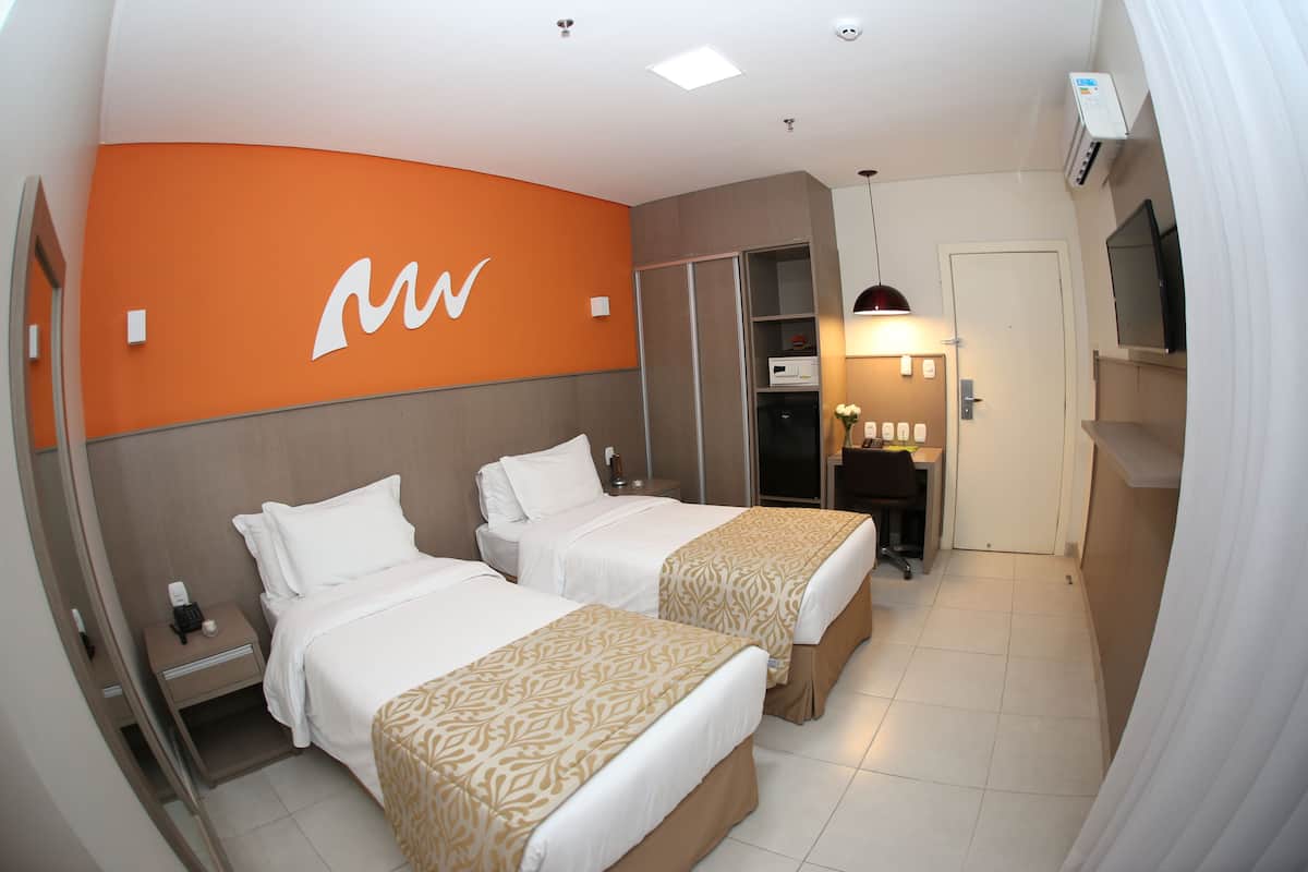 Hotelkamer met twee bedden, een minibar, een televisie en een badkamer met douche en toilet.