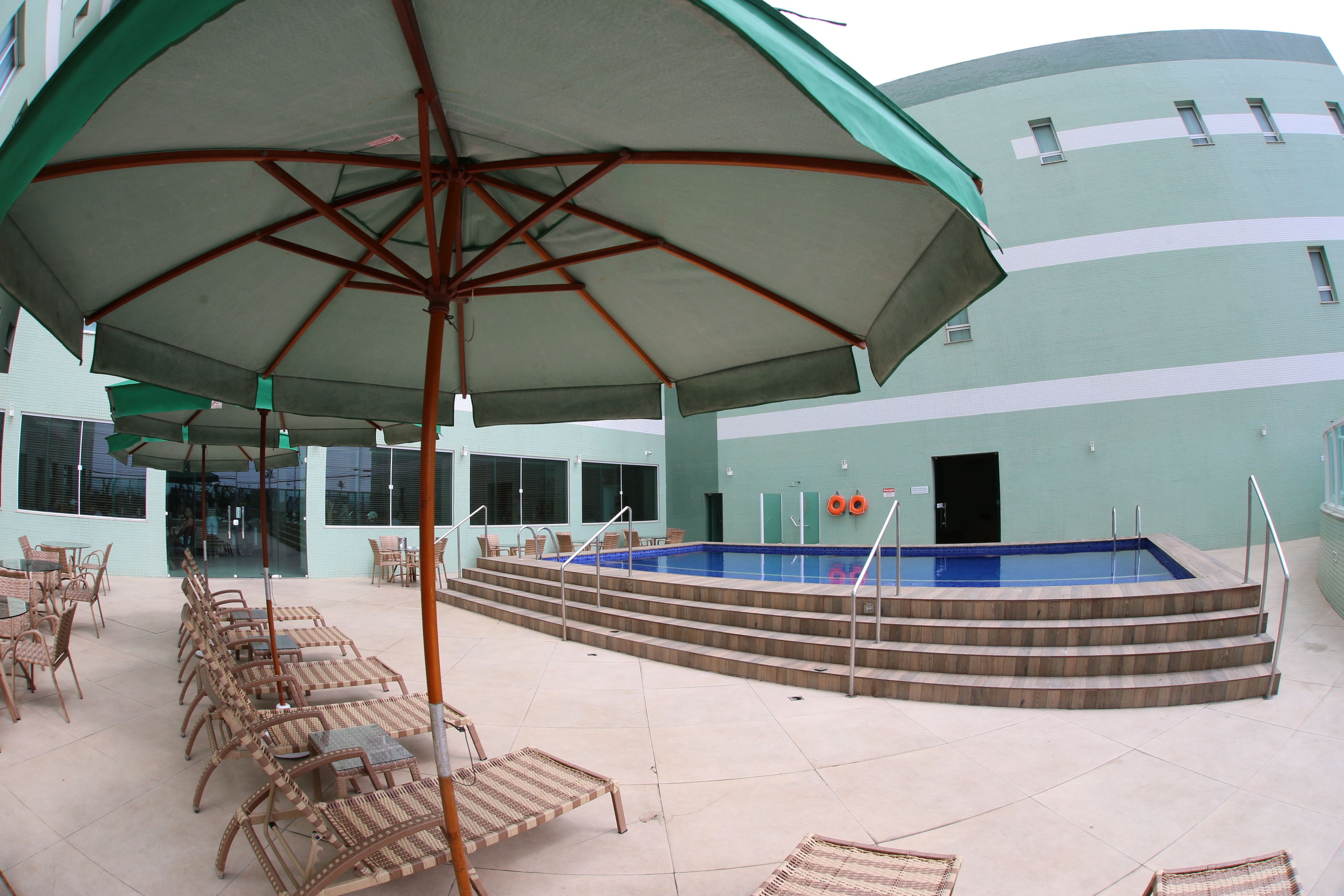 A pool area with lounge chairs and a covered seating area.