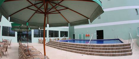A pool area with lounge chairs and a covered seating area.
