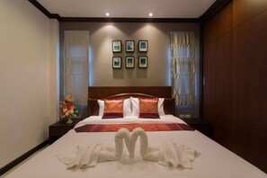 A hotel room with a large bed, a wooden headboard, and a wall with framed pictures. - The Unique Krabi Private Pool Villa (Krabi)