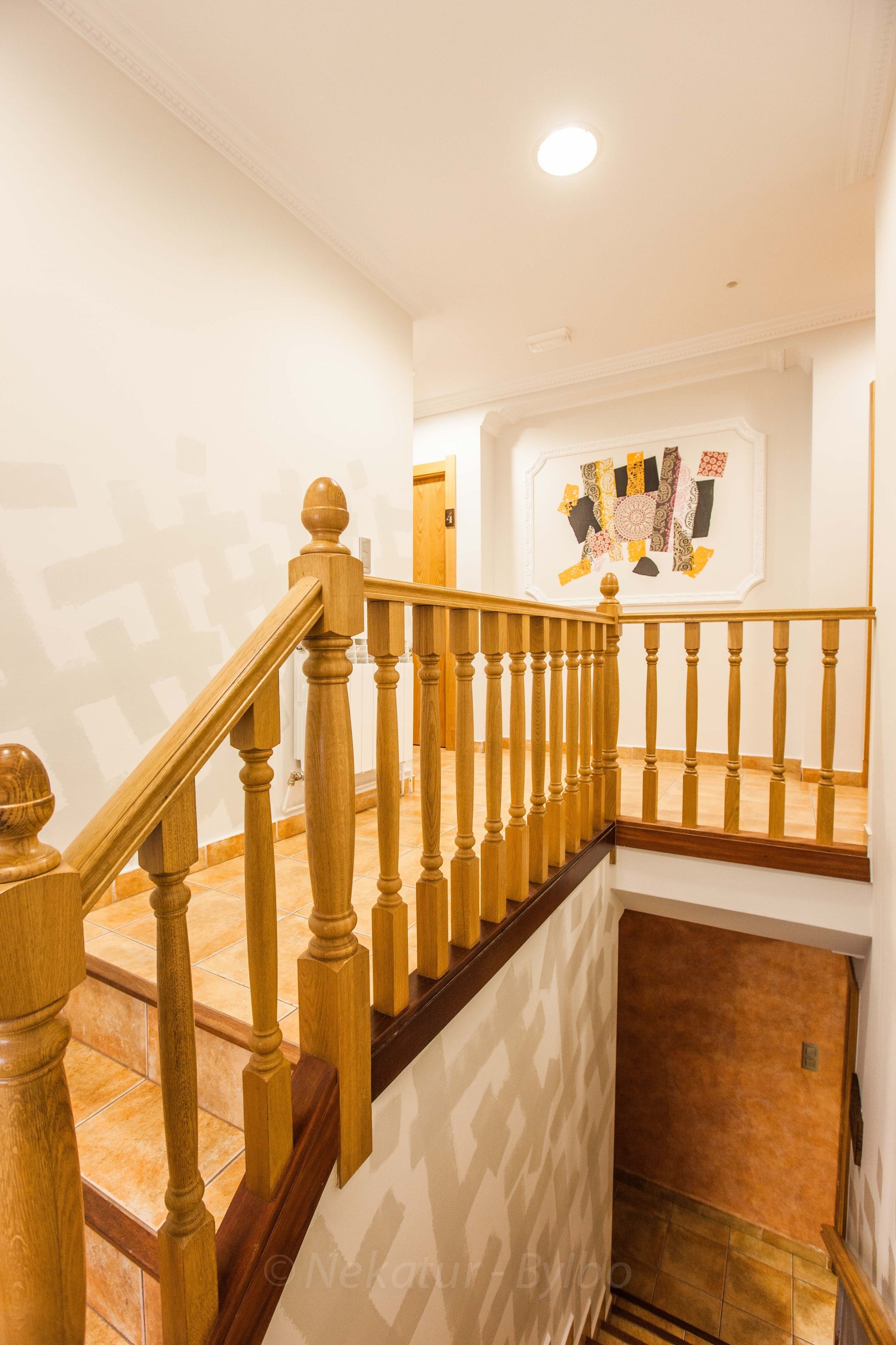 A wooden staircase with a patterned wall and a framed artwork above it.
