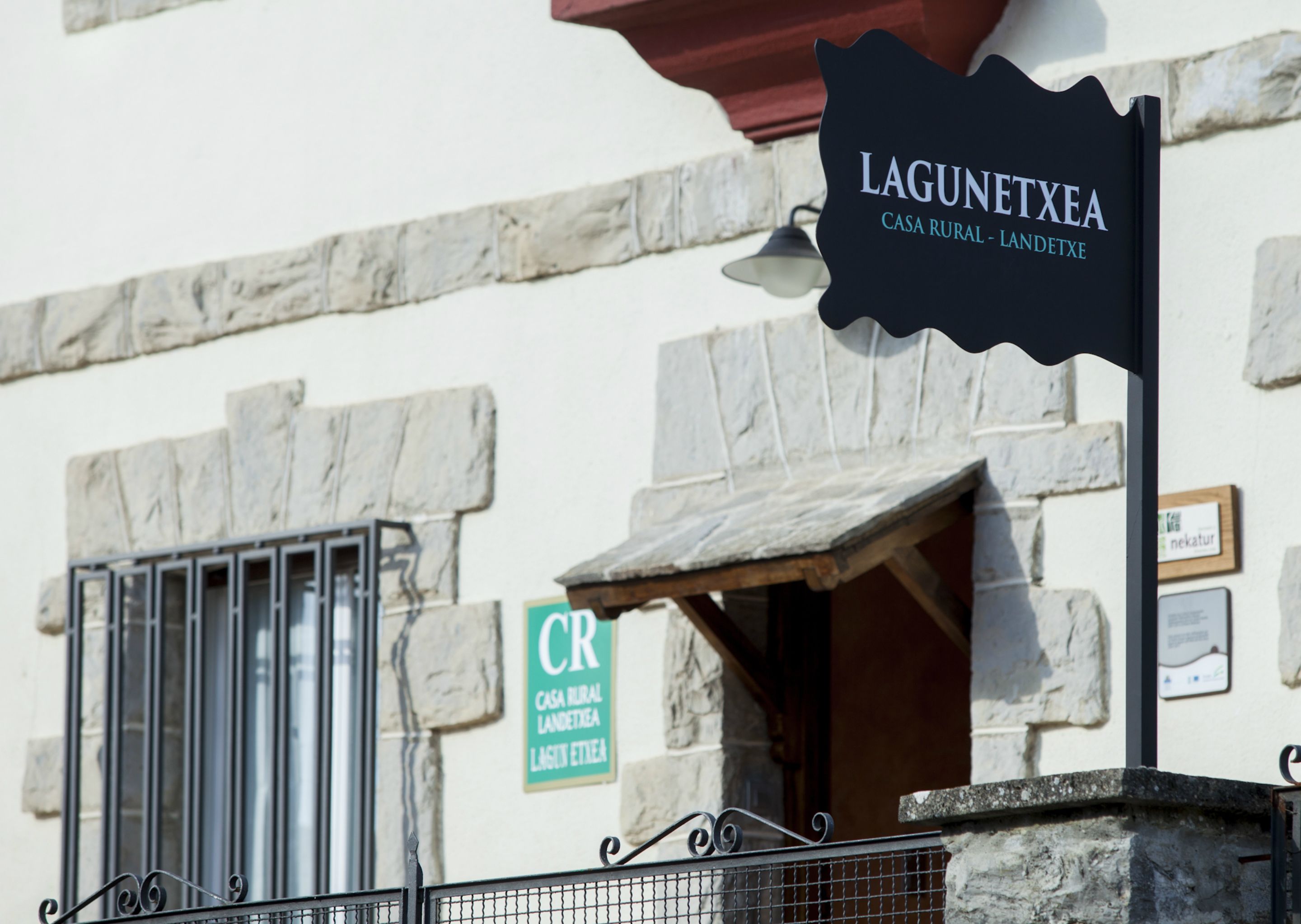 A sign for 'LAGUNETXEA CASA RURAL - LANDETXEA' with a rustic stone building in the background.