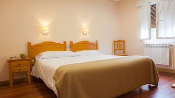 Une chambre à coucher avec un lit en bois, deux tables de chevet, une commode, une chaise et une fenêtre avec des stores.