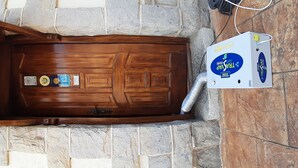 Una puerta de madera con un respiradero y una caja de servicios etiquetada como "TRAVAP" adosada a una pared de piedra.