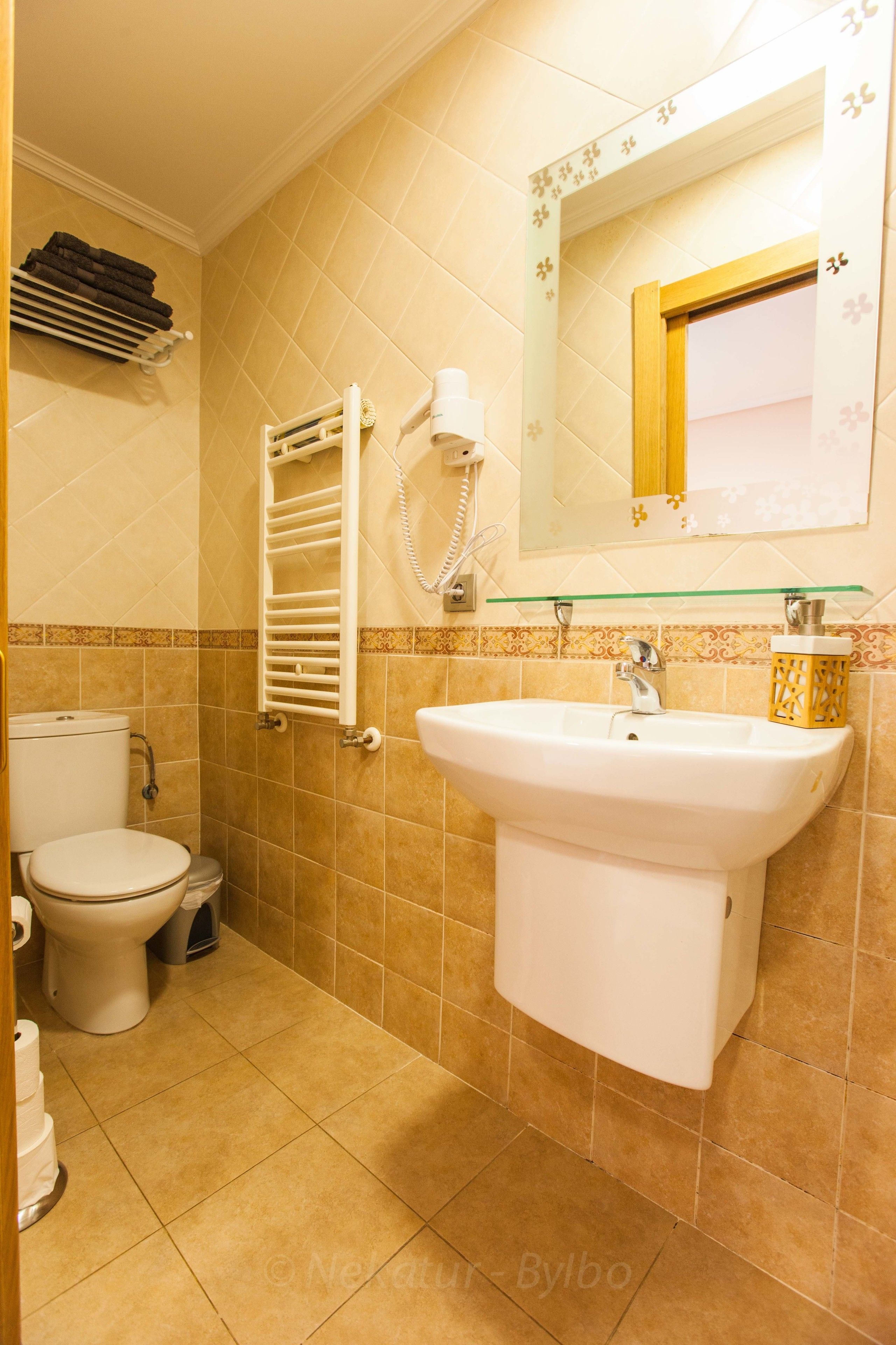 Un baño con inodoro, lavabo y barra para toallas.