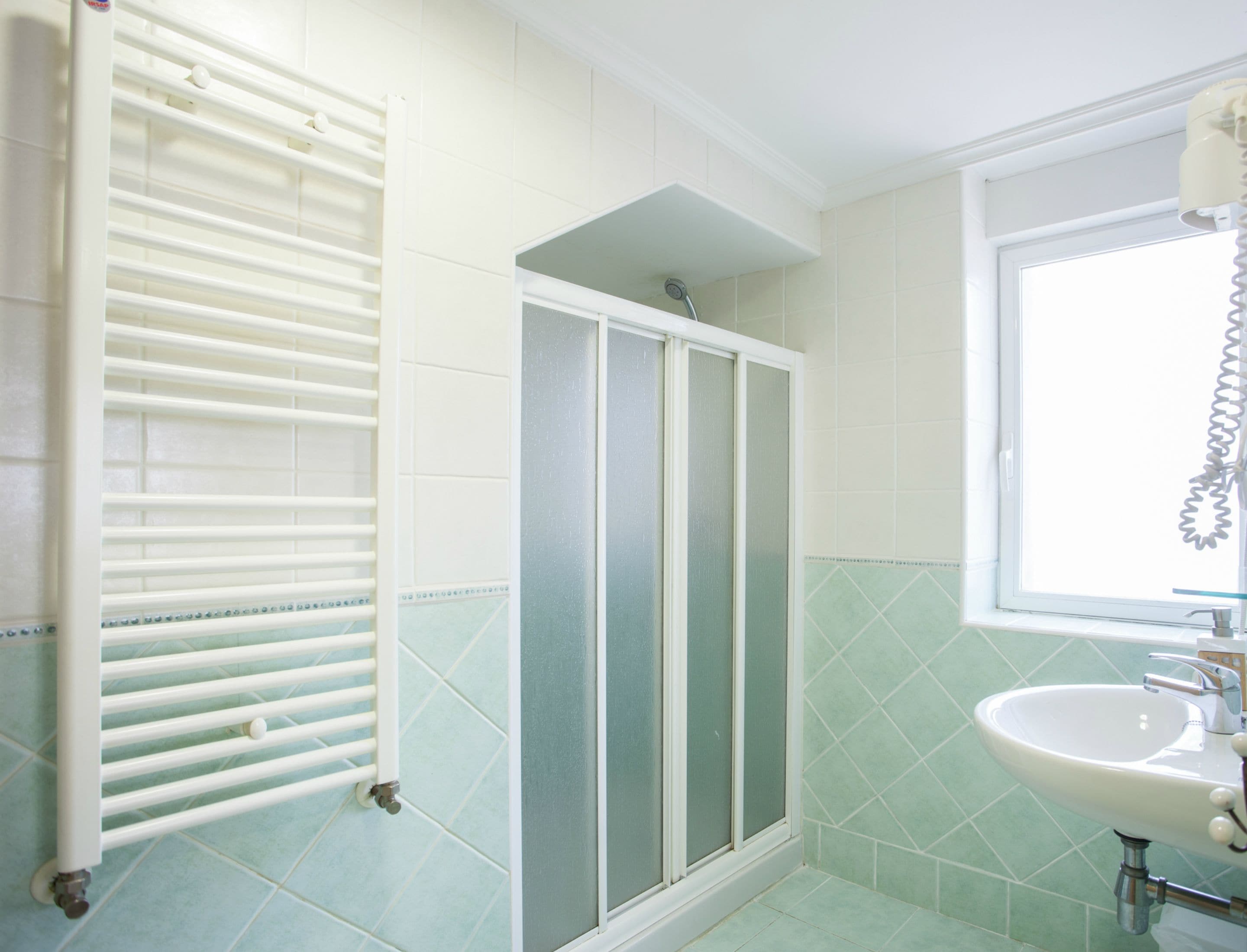 A bathroom with a shower, a sink, and a window.