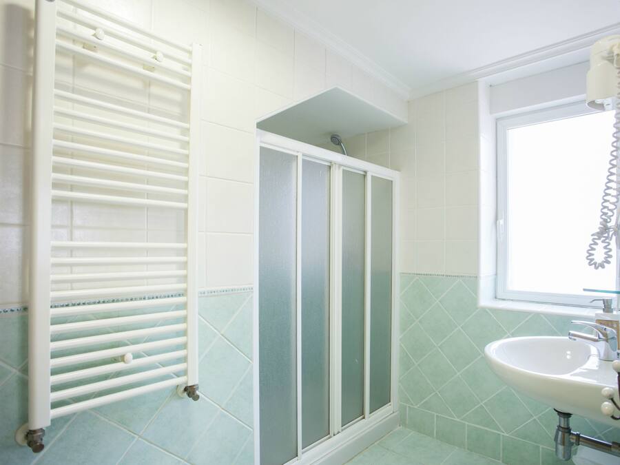 A bathroom with a shower, a sink, and a window.