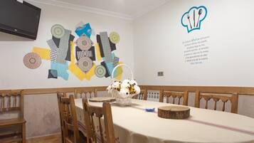 A dining room with a long table, wooden chairs, and a wall art piece.