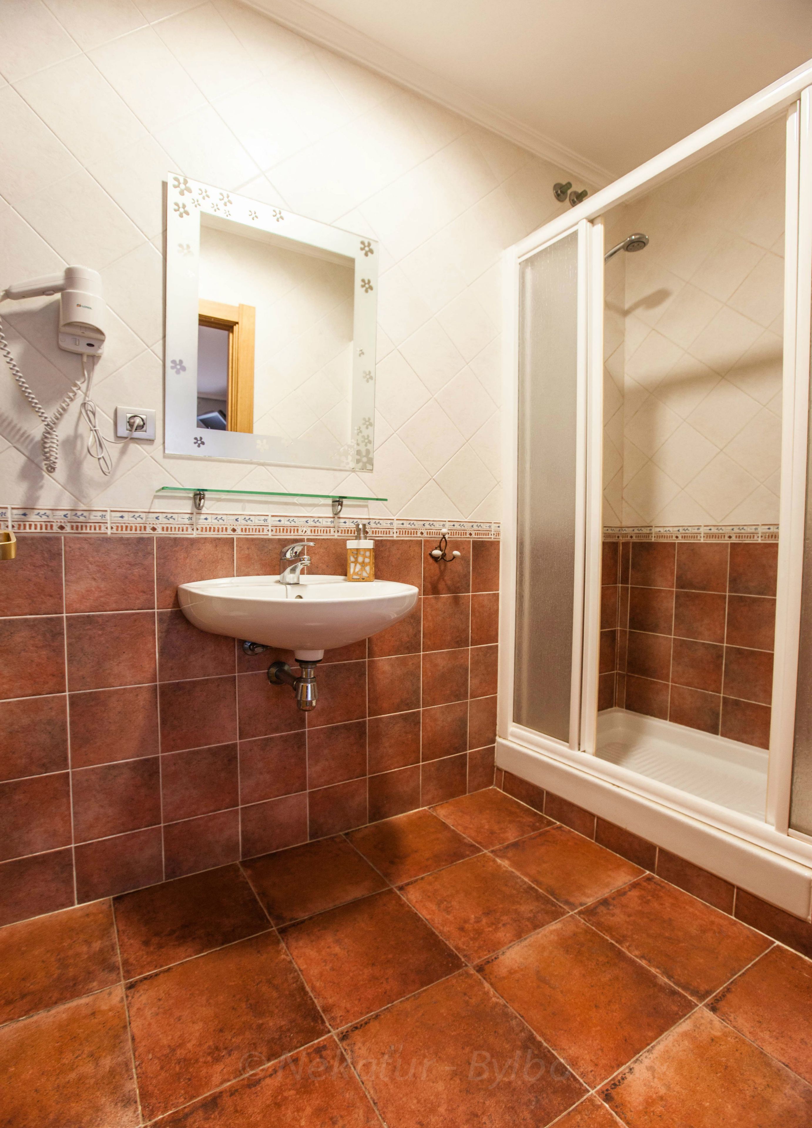 Een badkamer met een wastafel, spiegel en douche.