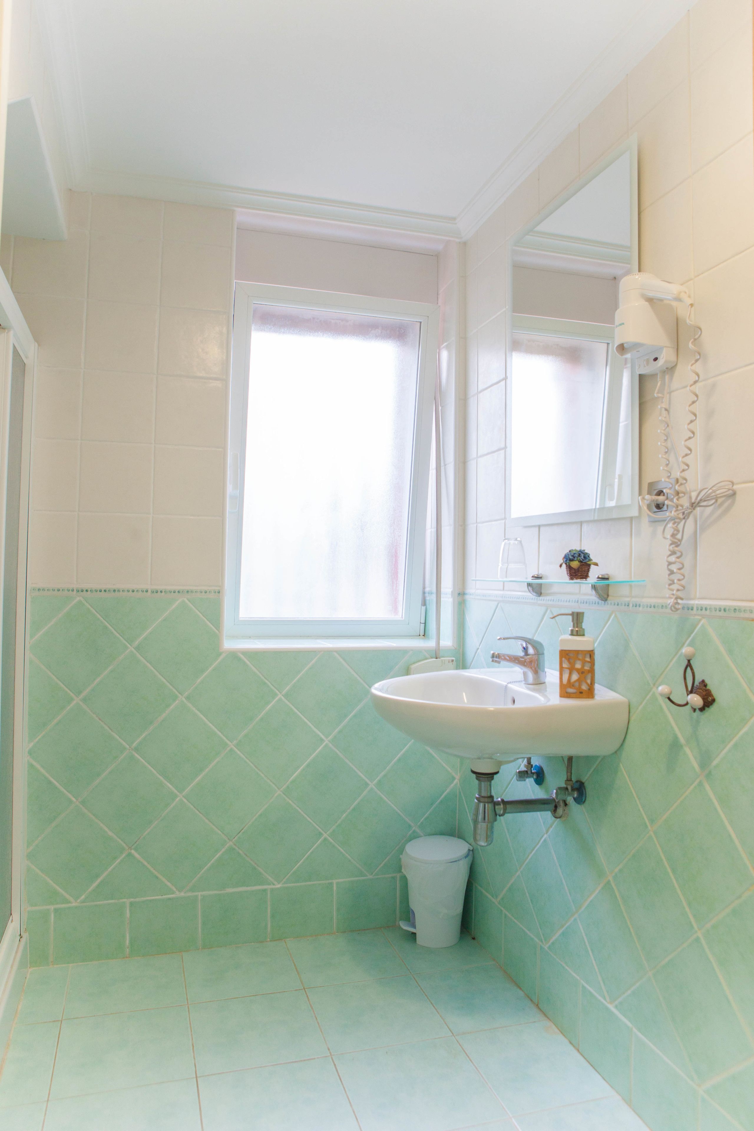 Un baño con lavamanos, espejo y ventana.