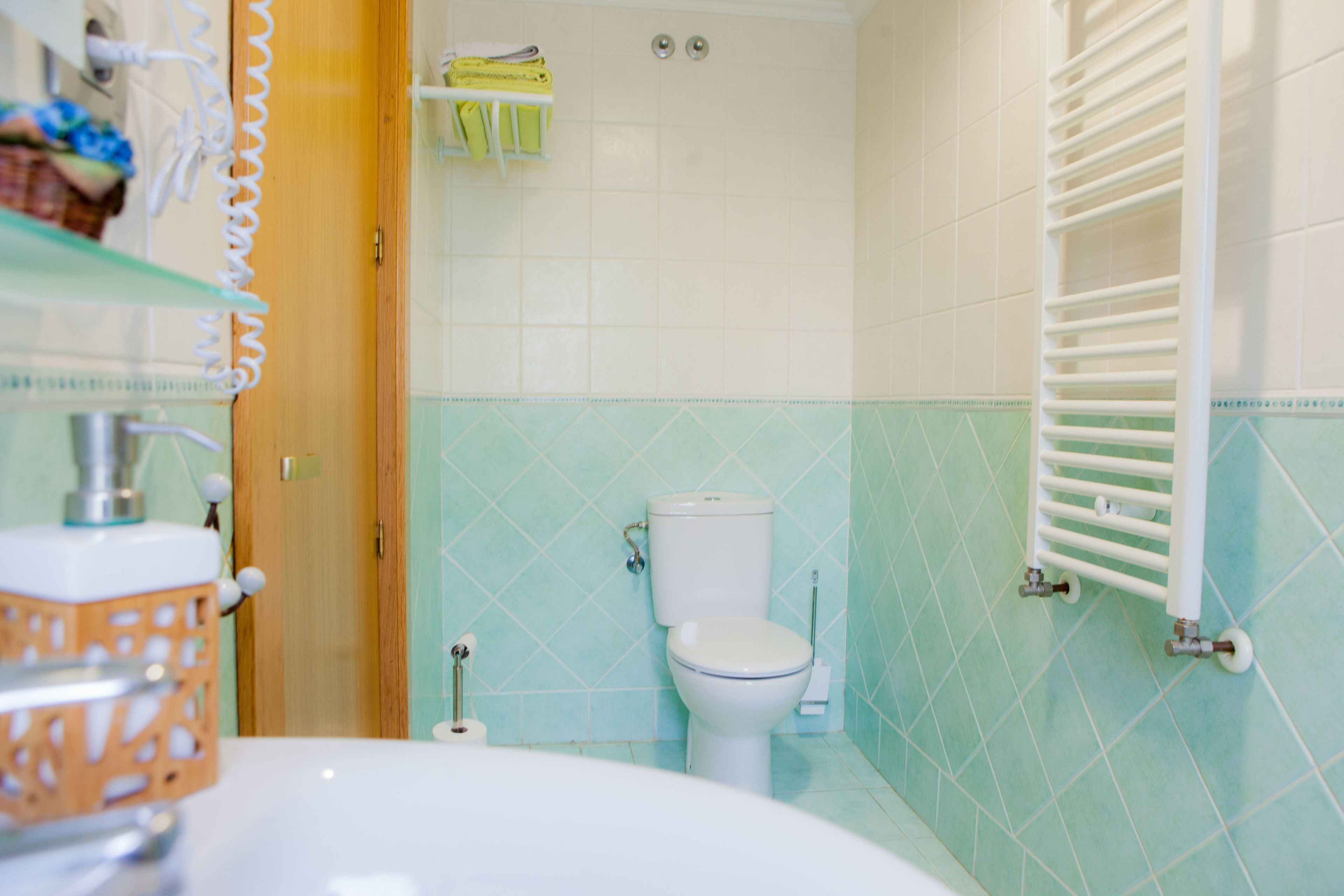 A bathroom with a toilet, a shower area, and a sink with a glass shelf.