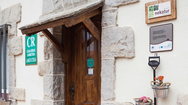 Un edificio de piedra con puerta de madera, un letrero de bienvenida y una señalización que indica un restaurante.