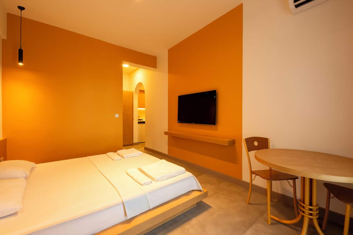 Een hotelkamer met een bed, een aan de muur bevestigde televisie, een eettafel en een stoel.