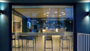 Eine Bar mit Glastrennwand, Stühlen und einer Theke.