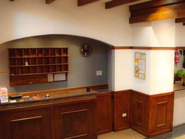 A kitchen with wooden cabinets, a built-in shelf, a clock, and a bulletin board.