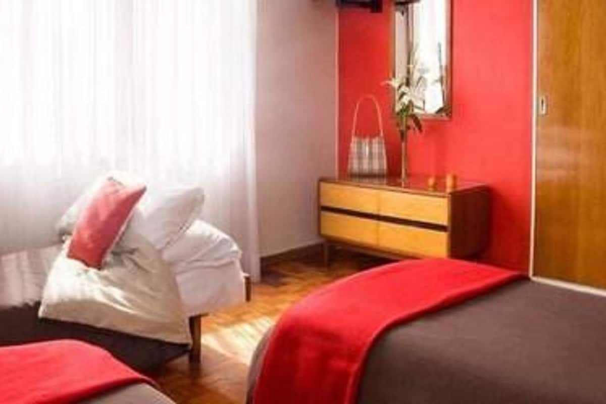 Un dormitorio con dos camas, un aparador de madera, un espejo y una ventana con cortinas.