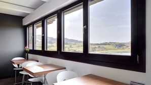 A room with a long table and chairs, large windows with a countryside view, and a modern design. - Hotel Rural Gaintza (Getaria)