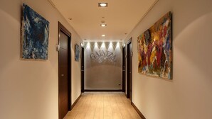 A hallway with a wooden floor, a frosted glass door with the name 'Galleria', and two abstract paintings on the walls. - Hotel Rural Gaintza (Getaria)