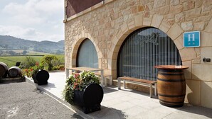 A stone building with a large arched entrance, a bench, and a wooden barrel outside. - Hotel Rural Gaintza (Getaria)