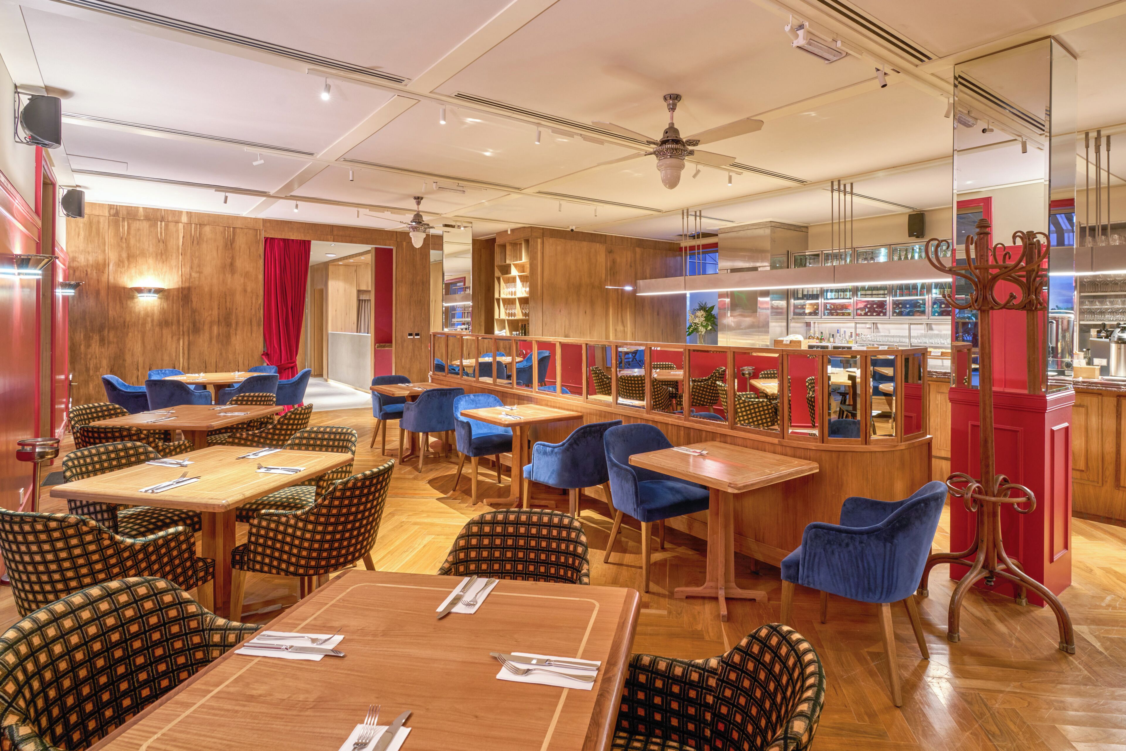 A restaurant with wooden tables and chairs, a bar area, and a ceiling fan.