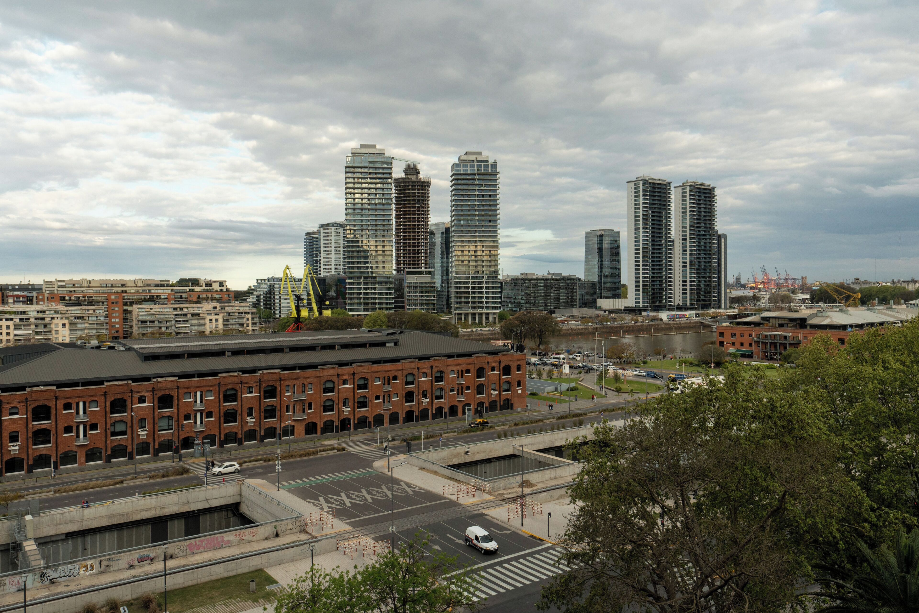 A cityscape with modern high-rise buildings, a large brick building, and a parking area.