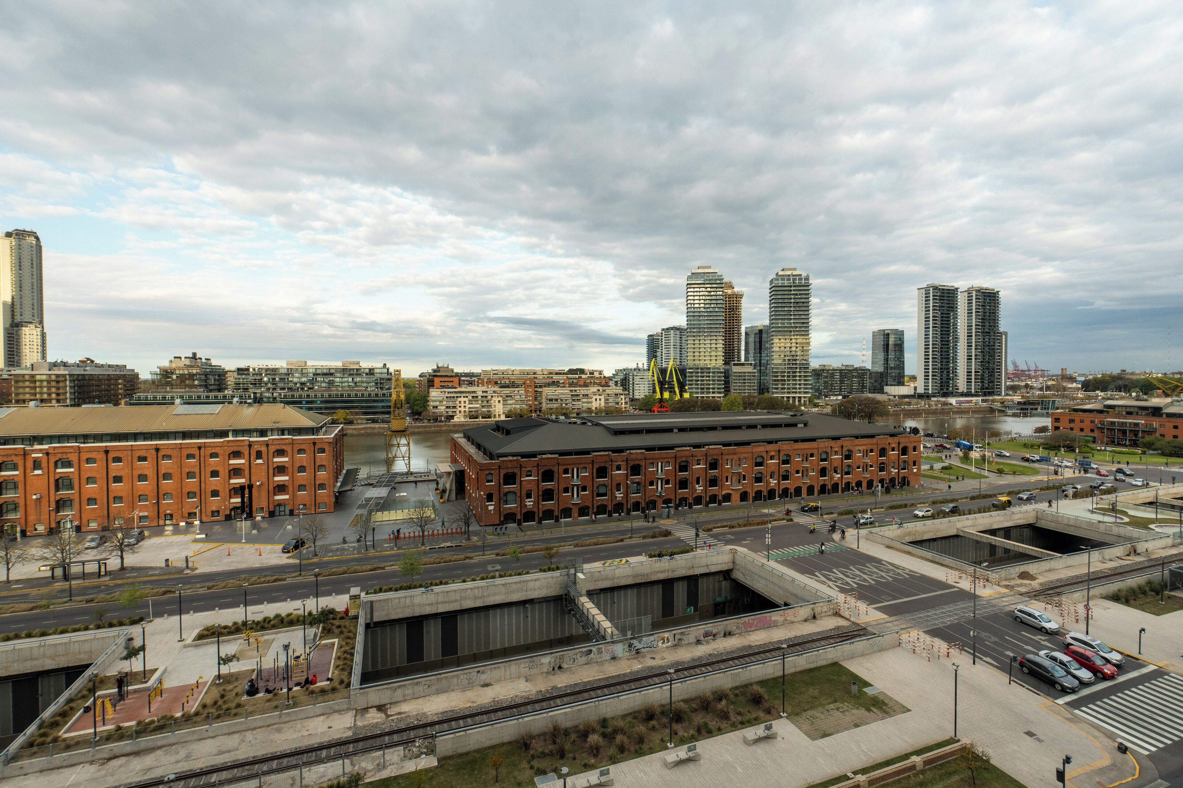 A cityscape with modern buildings, a large brick building, and a river.