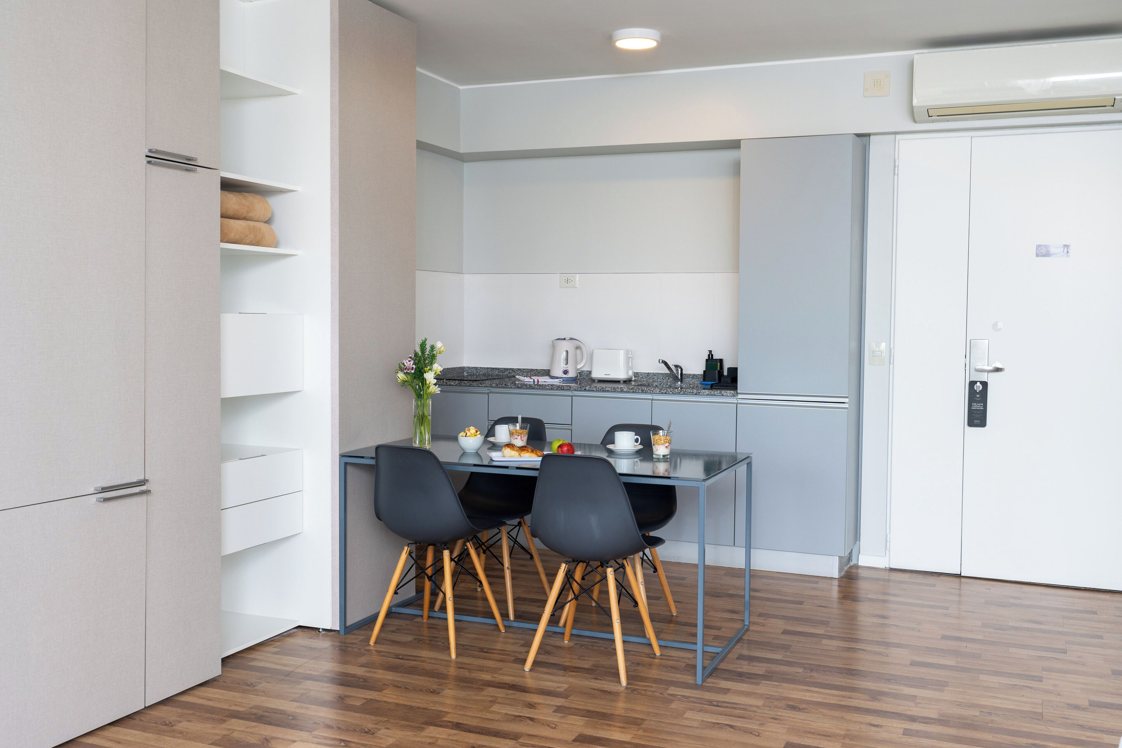 Una cocina moderna con una mesa de comedor, dos sillas y un refrigerador blanco.