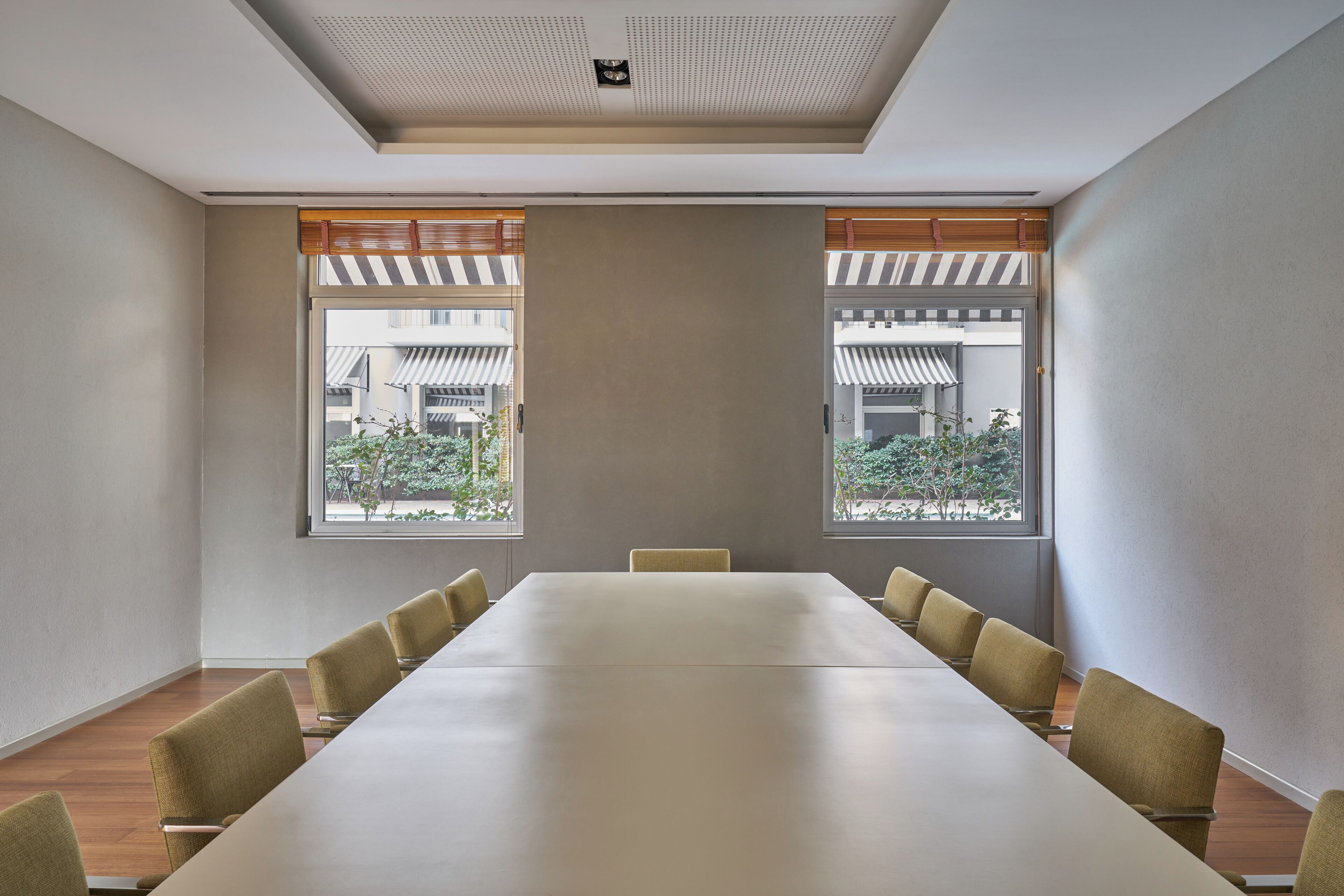 A conference room with a long table and chairs, large windows, and a view of traditional buildings outside.