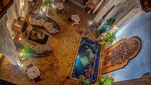Een sierlijke ruimte binnenshuis met een centrale fontein, zitgedeeltes en decoratieve zuilen.