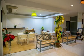 A modern dining area with white furniture, a wooden bench, and potted plants. - Z-Talay House (Krabi)