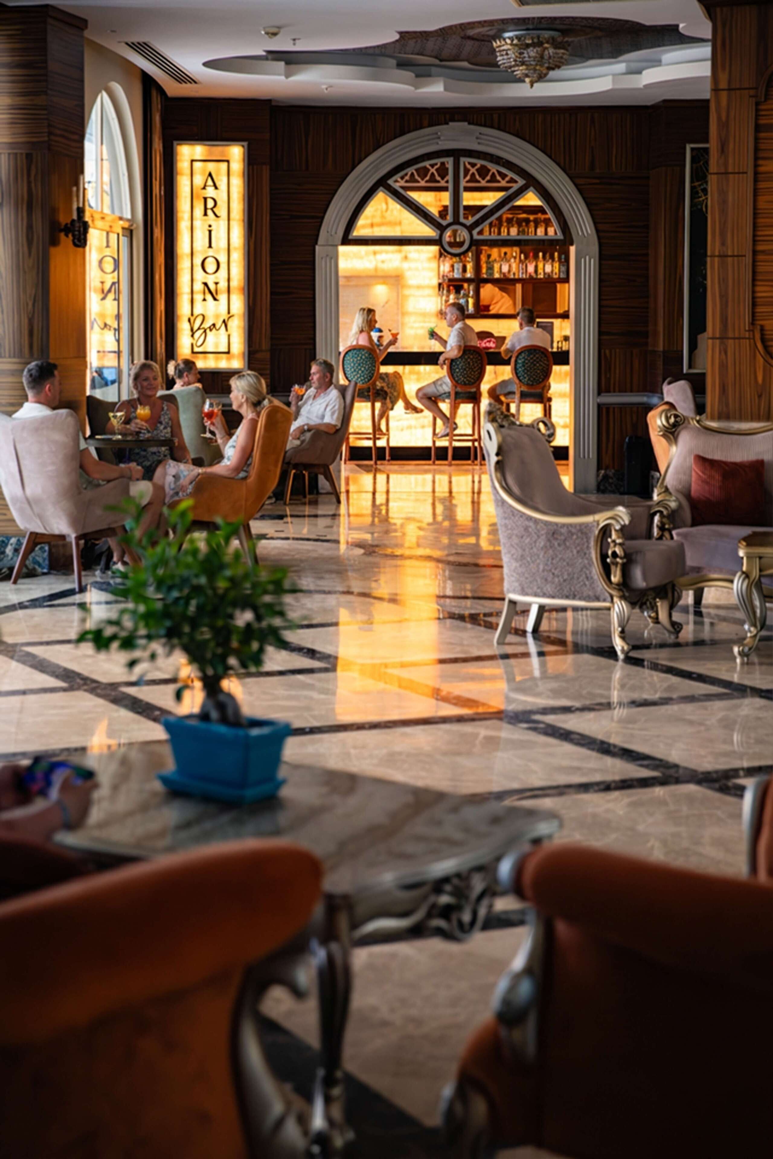 A lobby with a bar area, seating arrangements, and a large potted plant.