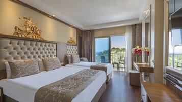 A hotel room with two large beds, a small desk, and a balcony with a view.