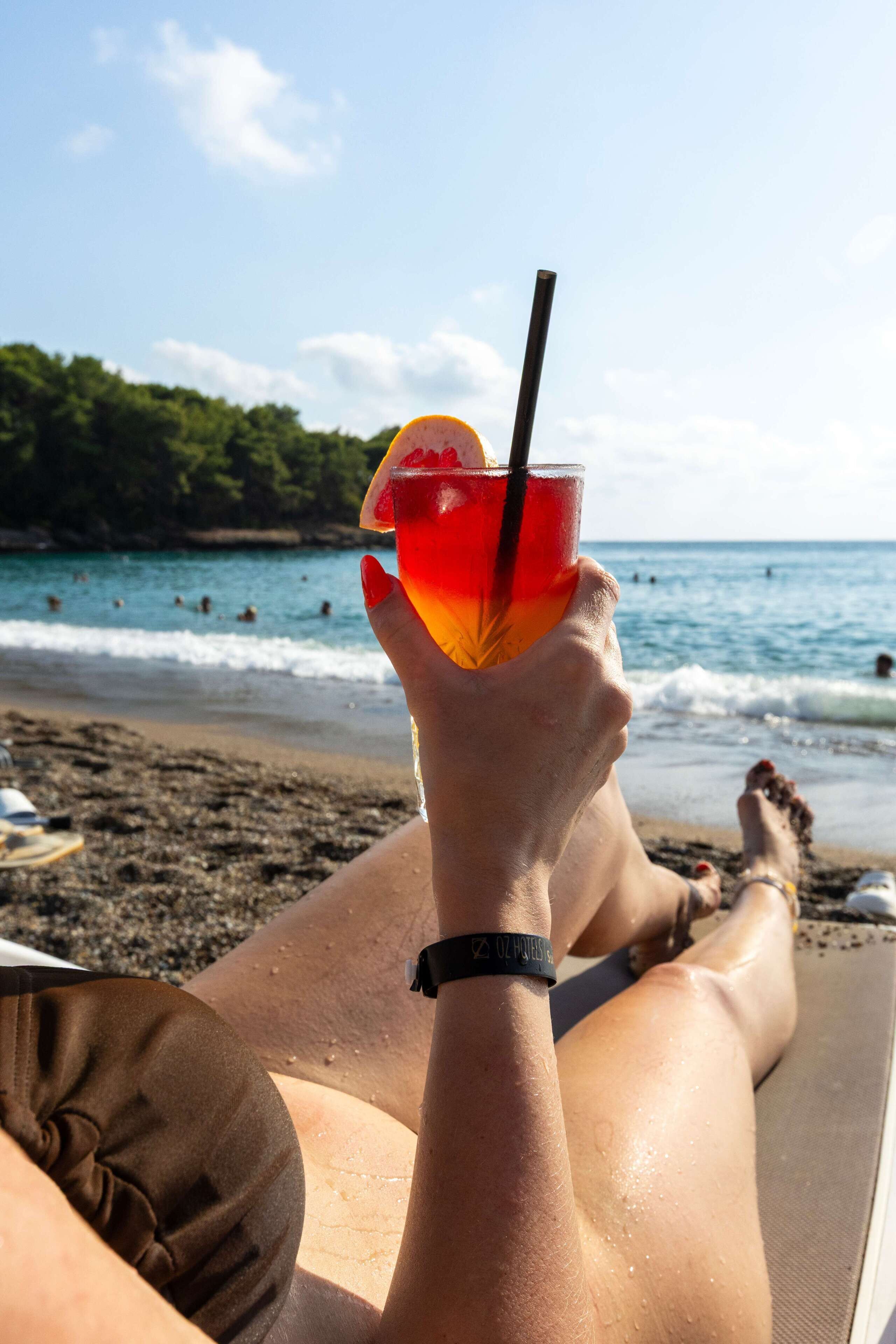 A person relaxing on a beach chair with a drink in hand.