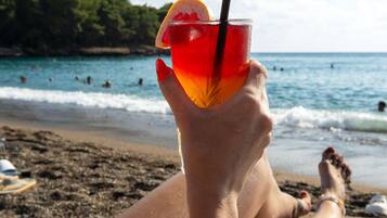 A person relaxing on a beach chair with a drink in hand.