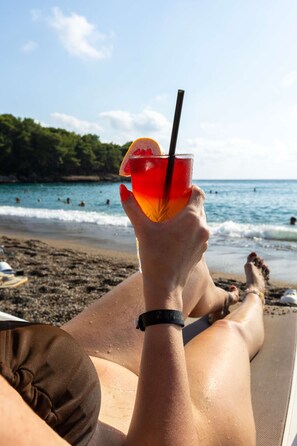 Une personne se détend sur une chaise longue, un verre à la main.