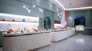 A modern hotel lobby with a long reception counter displaying an array of desserts and snacks.